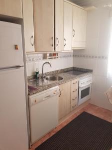 a kitchen with white cabinets and a sink and a refrigerator at La Linea in Puerto de Mazarrón