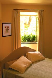 a bed with two pillows in front of a window at Residence Villa Firenze in Alassio