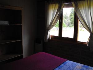 1 dormitorio con cama morada y ventana en Cabañas San Valentin en Lago Puelo