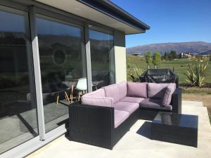 un sofá púrpura sentado en un patio con ventanas en Minaret Ridge Retreat en Wanaka