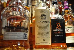 a group of bottles of whiskey on a shelf at The Galley Of Lorne Inn in Ardfern