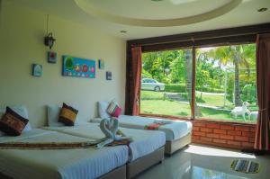 a room with two beds and a large window at Pai Iyara Resort in Pai