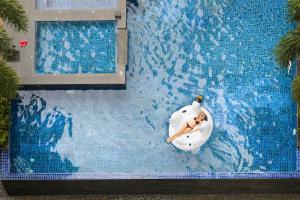 une personne posant sur un radeau gonflable dans une piscine dans l'établissement TTC Hotel - Michelia, à Nha Trang