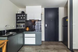 a kitchen with black cabinets and a black refrigerator at The Deck Condominium by Lofty in Patong Beach