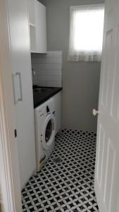 a bathroom with a washing machine in a white and black floor at Laurel House in Springwood