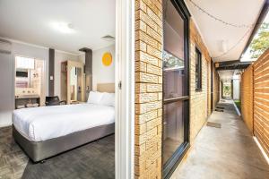 a bedroom with a bed next to a brick wall at Nightcap at Jamison Hotel in Penrith