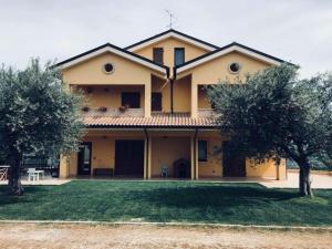 une grande maison jaune avec des arbres devant elle dans l'établissement Villa Lò, à Chieti