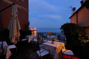 eine Terrasse mit Tischen, Stühlen und einem Sonnenschirm in der Unterkunft Residence Le Terrazze in Alassio