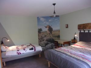 1 dormitorio con un mural de una vaca en la pared en Chambre d'hôtes Le Cascadou, en Banassac