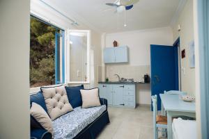 a living room with a blue couch and a kitchen at Maria Studios in Poros