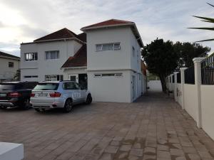 un coche aparcado frente a una casa blanca en Beachway Guesthouse, en Port Elizabeth