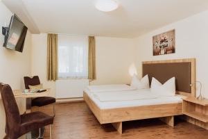 a bedroom with a bed and a table and a desk at Gästehaus Hötzl in Galgweis