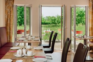 een eetkamer met een tafel, stoelen en ramen bij Gästehaus Hötzl in Galgweis