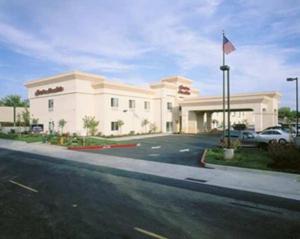 un grand bâtiment blanc avec un drapeau devant lui dans l'établissement Hampton Inn & Suites Sacramento-Auburn Boulevard, à Sacramento