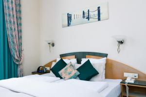 Schlafzimmer mit einem Bett mit weißen und grünen Kissen in der Unterkunft Hotel Moby Dick by WP hotels in Blankenberge