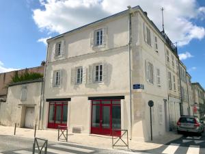 - un bâtiment blanc avec des portes rouges dans une rue dans l'établissement Centre Ville Location, à La Rochelle
