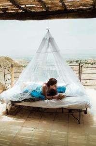 una mujer acostada en una cama bajo una red en Beit Al Fannan en Ţabaqat Faḩl