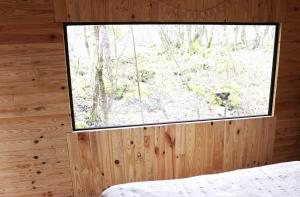 a bedroom with a large window in a wooden cabin at Le Domaine De La Genette in Paussac-et-Saint-Vivien