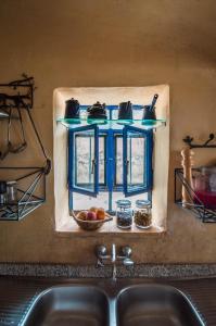 un évier de cuisine avec une fenêtre bleue au-dessus. dans l'établissement Beit Al Fannan, à Ţabaqat Faḩl