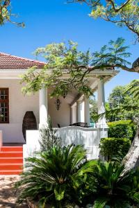 
a white and red house with a tree in front of it at 5 Camp Street Guesthouse & Self-catering in Cape Town
