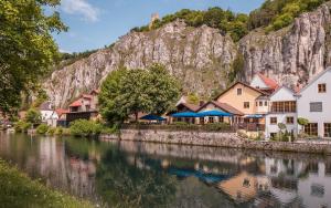 un village au bord d'une rivière avec une montagne en arrière-plan dans l'établissement Bierhotel - Hotel & Brauereigasthof Schneider, à Essing