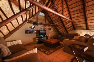 a living room with couches and a tv in a attic at Khaya Umdani Guest Houses in Marloth Park
