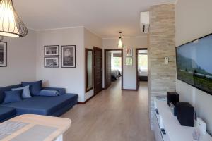 a living room with a blue couch and a tv at Apartamenty Starówka - Riverside II in Szczecin
