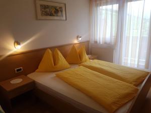 1 dormitorio con 1 cama con sábanas amarillas y ventana en Ferienwohnung Winklerhof, en Maranza