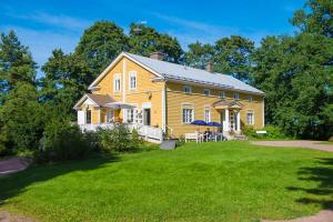 una casa amarilla con césped delante en Koivulan Kartano, en Lohja