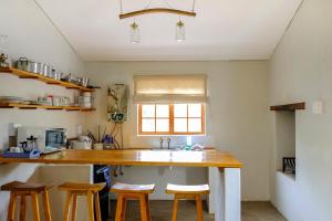 a kitchen with a sink and some wooden stools at De Bos Cottages in Montagu