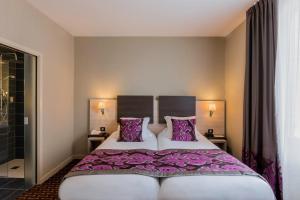a bedroom with a large bed with purple sheets and pillows at Best Western Plus Richelieu in Limoges