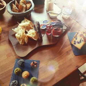 una mesa de madera con un plato de pan y repostería en Chambres d'Hôtes Les Ifs, en Montsûrs