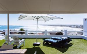 a patio with an umbrella and chairs and the ocean at 16 Mile View in Yzerfontein