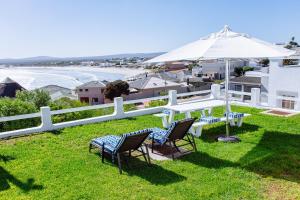 um pátio com uma mesa, cadeiras e um guarda-sol em 16 Mile View em Yzerfontein