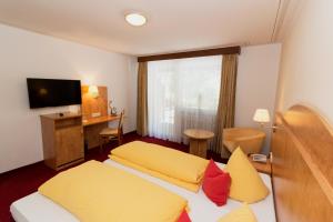 a hotel room with two beds with yellow and red pillows at Hotel Cortina in Höchenschwand