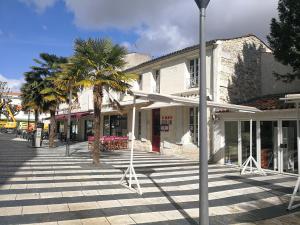 une rue avec des palmiers en face d'un bâtiment dans l'établissement La Loge du Theatre - Saintes, à Saintes