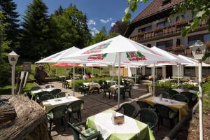 an outdoor restaurant with tables and white umbrellas at Hotel Cortina in Höchenschwand
