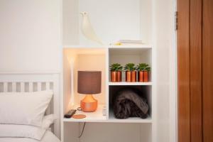 une étagère blanche avec des plantes et une lampe sur un lit dans l'établissement The Woodpecker Snug, à Nottingham