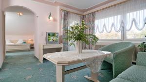 - un salon avec une table, des chaises et une télévision dans l'établissement Gästehaus Fertschey, à Velden am Wörther See