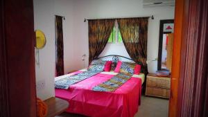 a bedroom with a bed with pink sheets and a window at Kingfishers Apartments in Bijilo