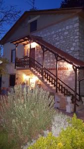 a stone house with a wooden porch with lights at Casale delle ginestre. in Castel Madama
