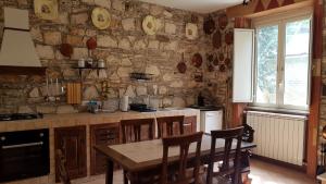 a kitchen with a table and chairs and a stone wall at Casale delle ginestre. in Castel Madama