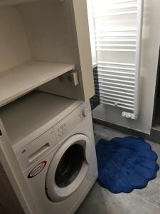 - un lave-linge dans une pièce dotée d'un tapis bleu dans l'établissement Les cigales de la mer Place de la libération, au Grau-du-Roi