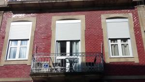 a brick building with a balcony and three windows at Apartamento da Ferreirinha in Peso da Régua