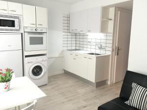 a kitchen with white cabinets and a washer and dryer at Aiguaneu Sa Carbonera in Blanes