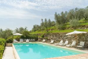 una piscina con tumbonas y sombrillas en Casale il Gualdo by VacaVilla, en Radda in Chianti