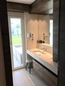 a bathroom with a sink and a mirror and a stool at Appartement Suite Delta Resort in Ascona