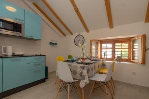 a kitchen with a table with chairs and a clock on the wall at Apartments Giro Korcula in Korčula
