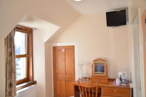a room with a desk and a tv on the wall at The Quaich B&B in Inverness