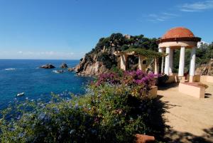 a gazebo next to the ocean with flowers at Aiguaneu Sa Carbonera in Blanes